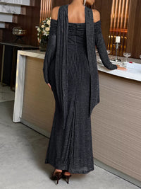 Person wearing a long black dress with a textured pattern in an indoor setting.