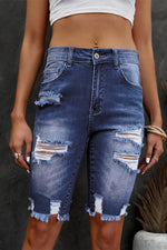 Person wearing a distressed denim skirt against a dark background