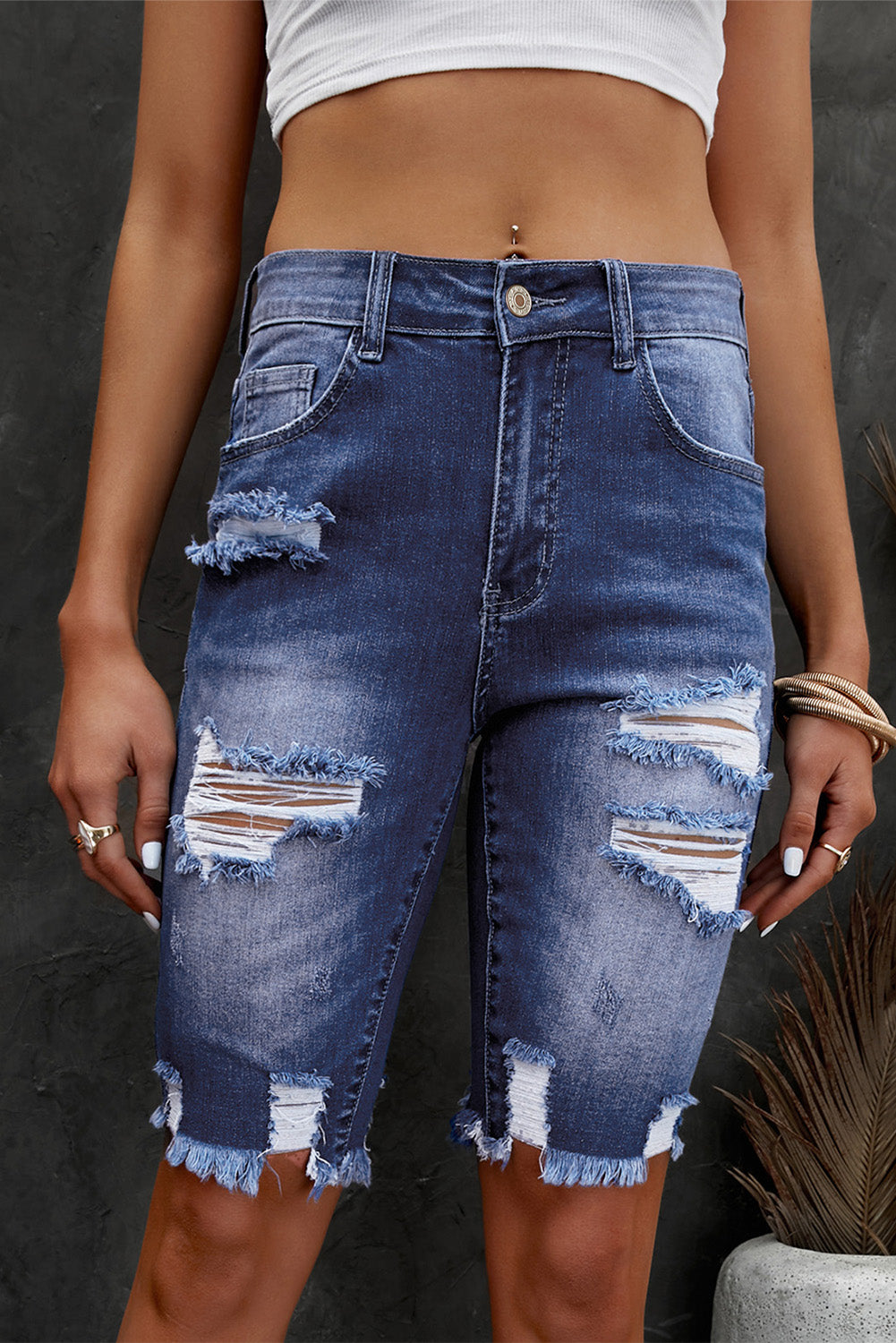 Person wearing a distressed denim skirt against a dark background
