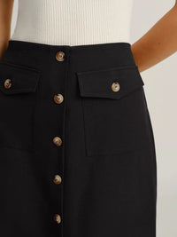 Black skirt with gold buttons on a plain background