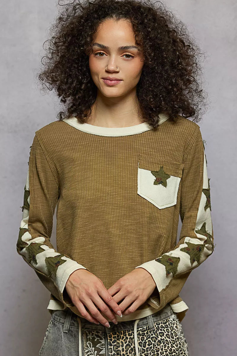 Woman wearing a brown long-sleeve shirt with star patterns on a gray background