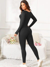 Woman wearing a black bodysuit in a room with white walls and decorative elements.