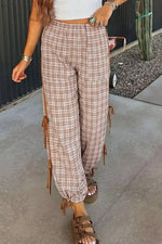 Person wearing plaid pants with tassels on a sidewalk.