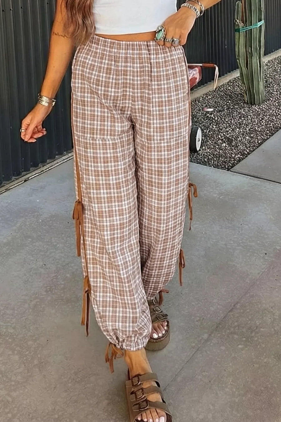 Person wearing plaid pants with tassels on a sidewalk.