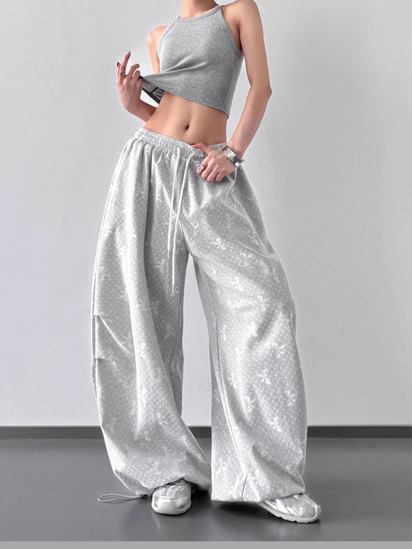 Person wearing a gray crop top and wide-leg pants on a plain background