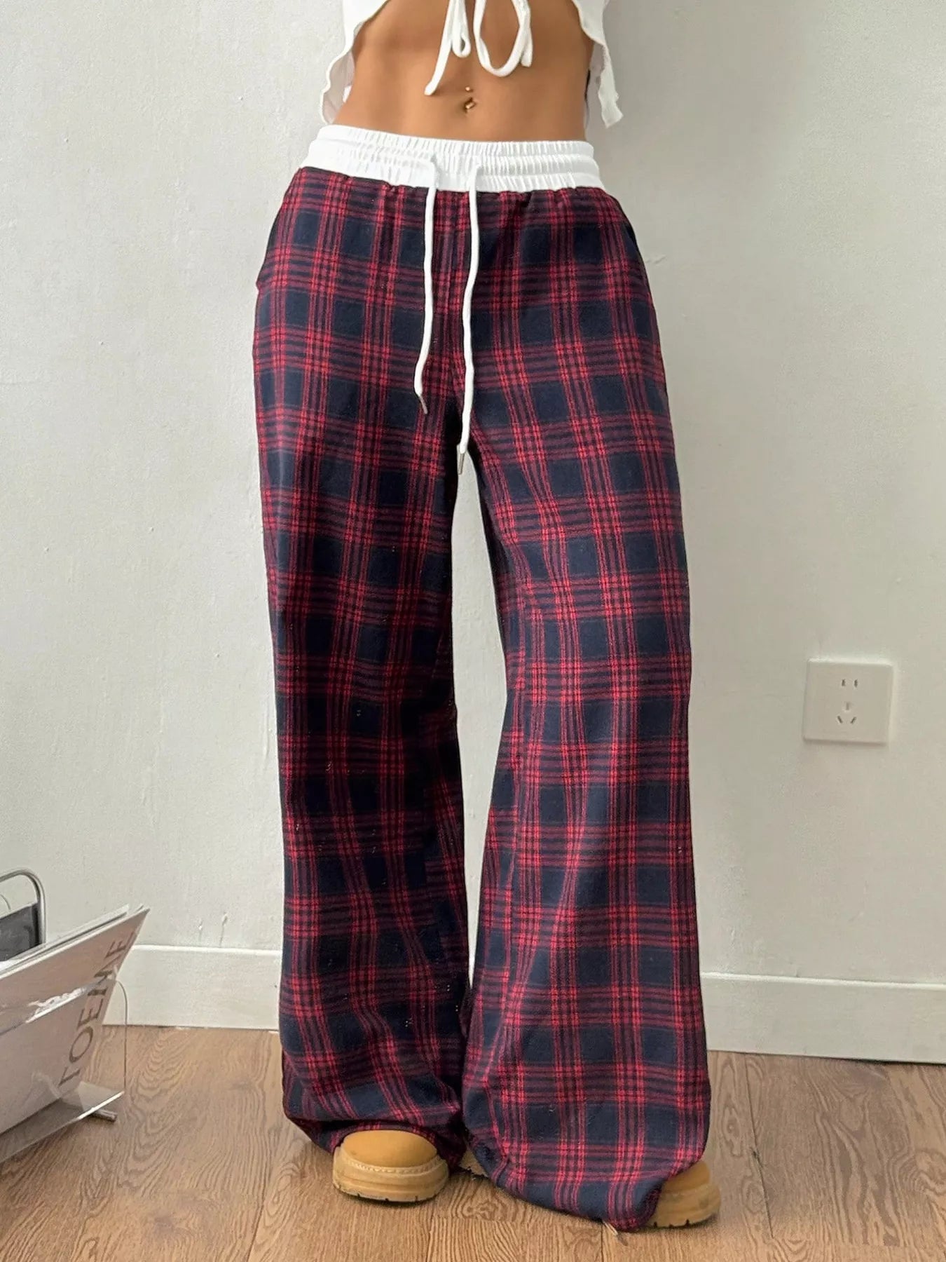 Person wearing red and blue plaid pajama pants in a room.