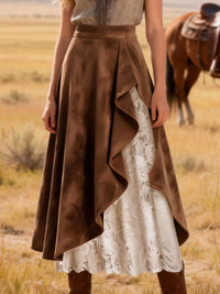 Person wearing a brown skirt with lace detailing in a desert setting with a horse in the background.