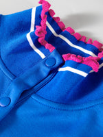 Blue baby romper with pink and white trim on a light gray background