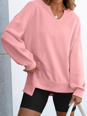 Person wearing a pink sweatshirt and black shorts against a light gray background