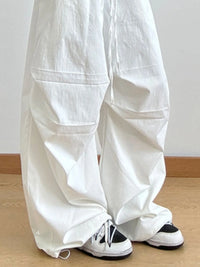 White wide-leg pants worn by a person on a wooden floor with a white wall background