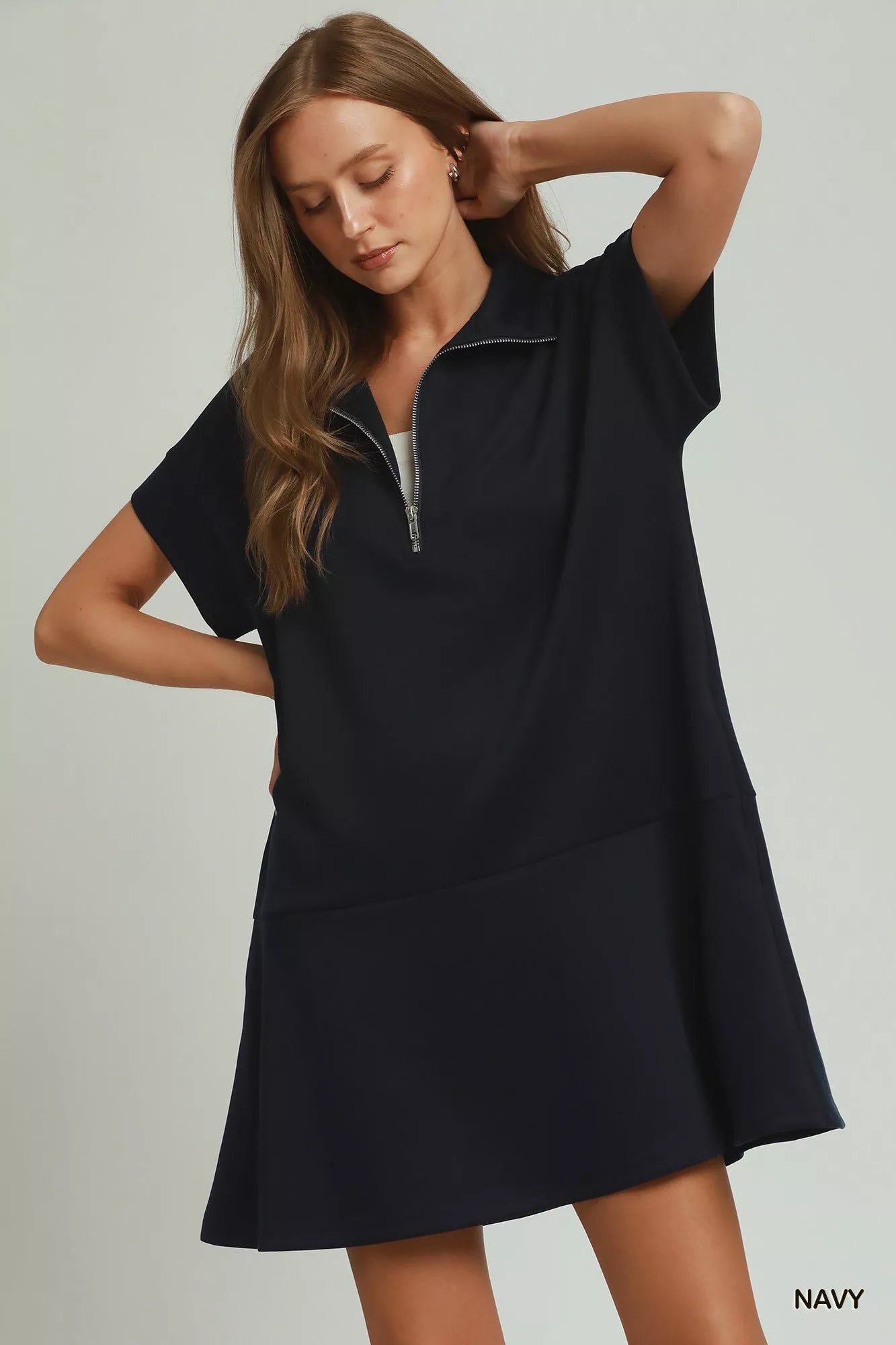 Woman wearing a navy dress with a zipper on a light gray background