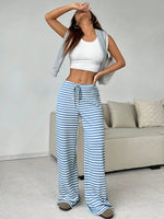 Woman wearing a white crop top and blue striped pants in a living room.