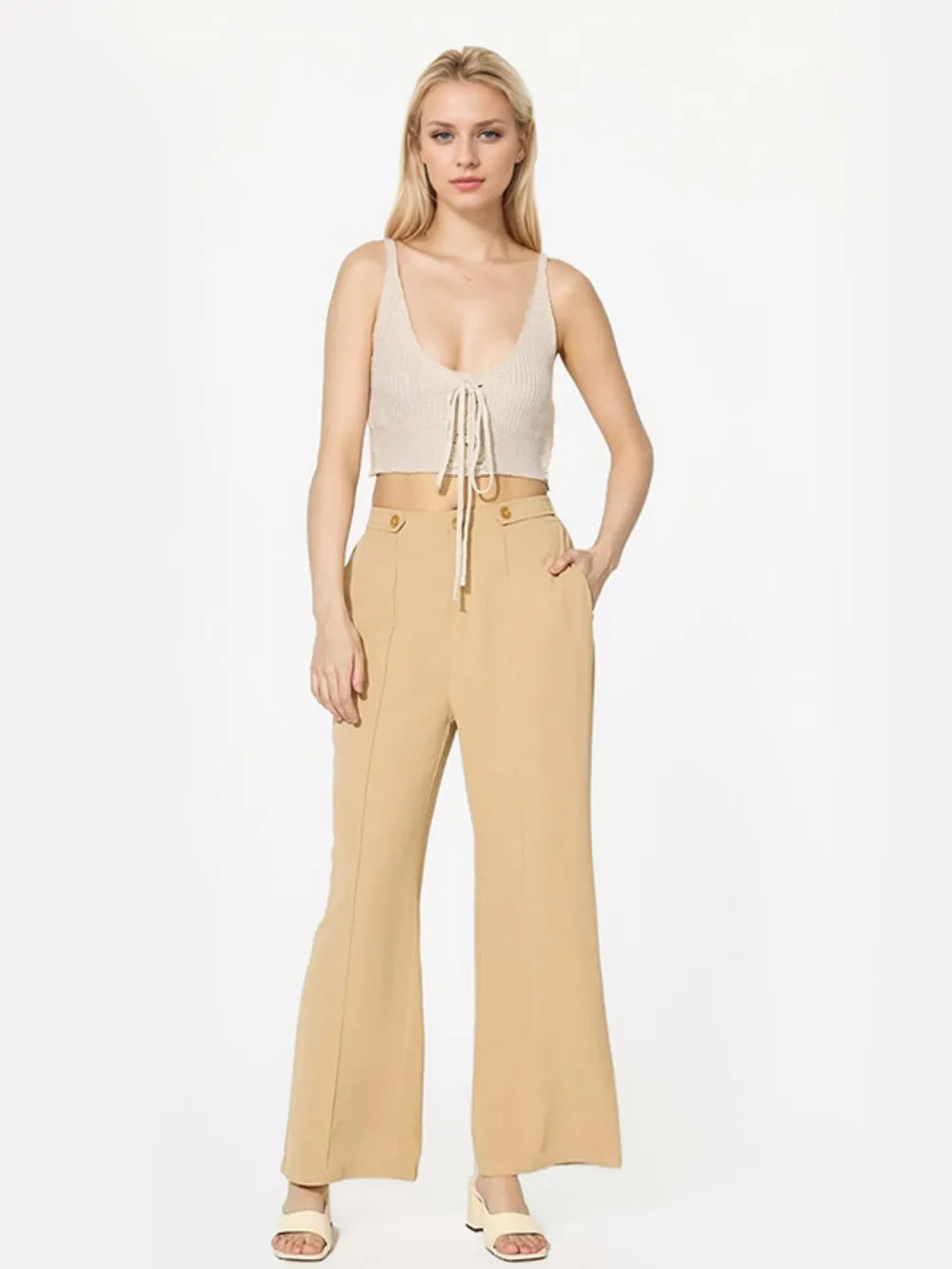 Woman wearing a beige top and pants on a white background
