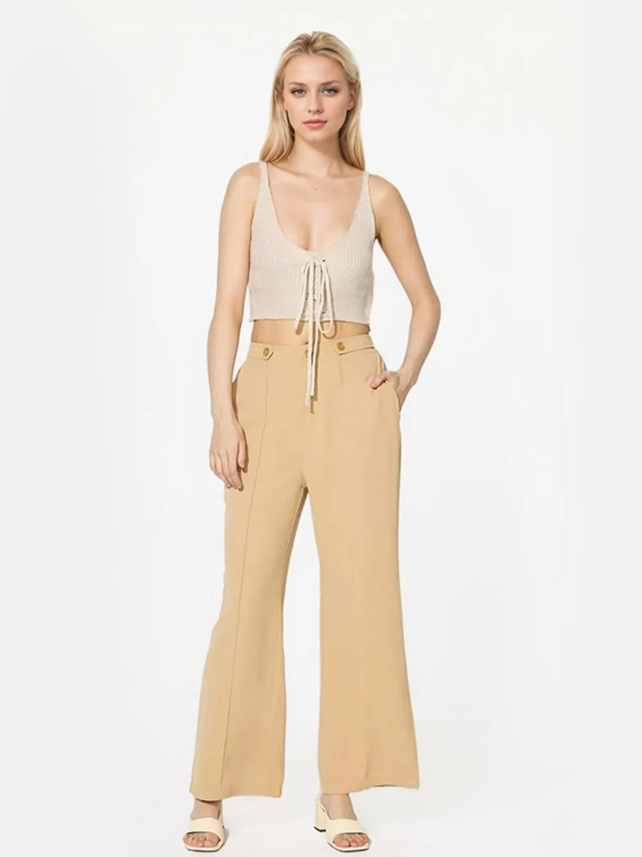 Woman wearing a beige top and pants on a white background