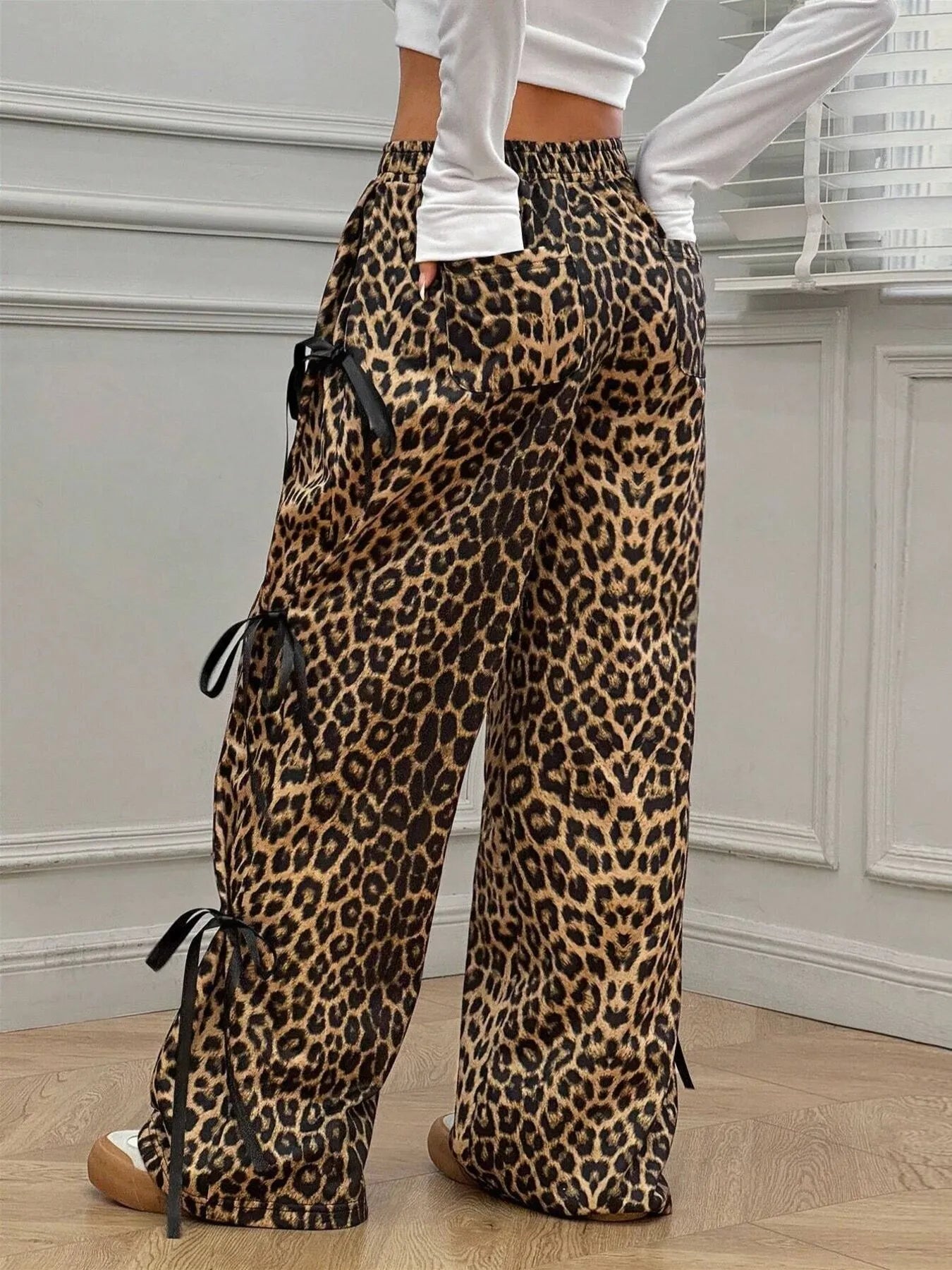 Leopard print pants with drawstring details worn by a person indoors.
