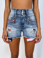 Denim shorts with patches and frayed hem on a plain background