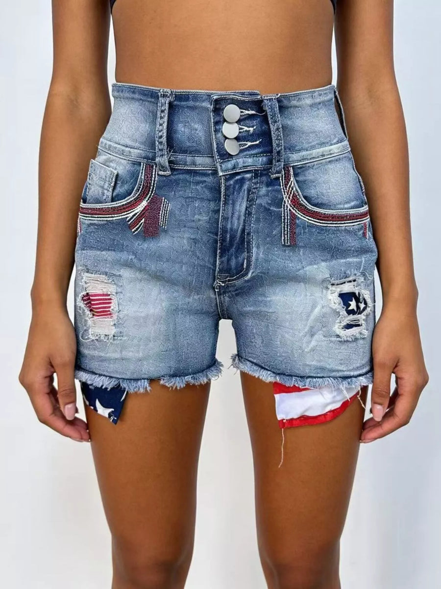 Denim shorts with patches and frayed hem on a plain background