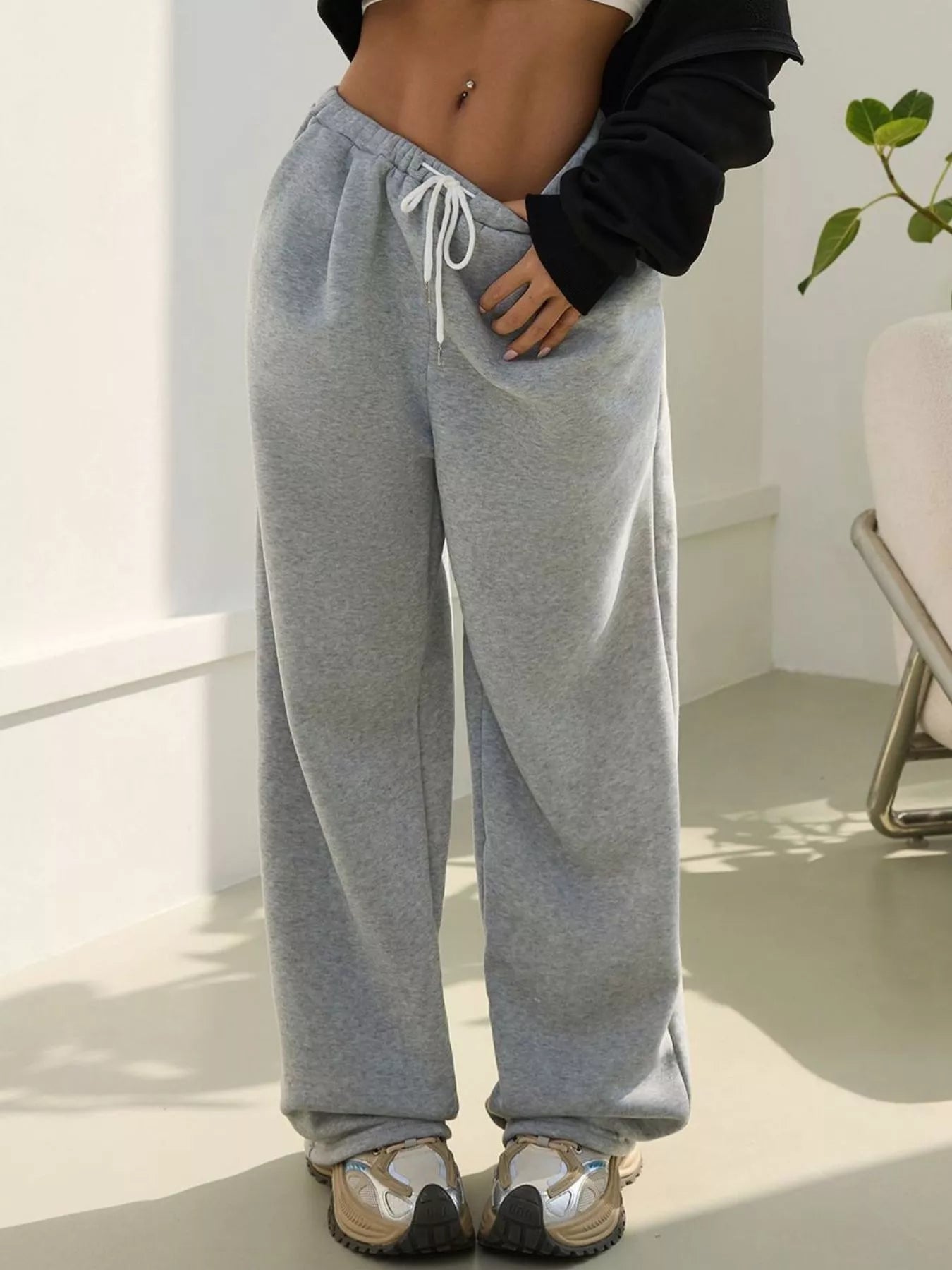 Person wearing gray sweatpants in a minimal indoor setting