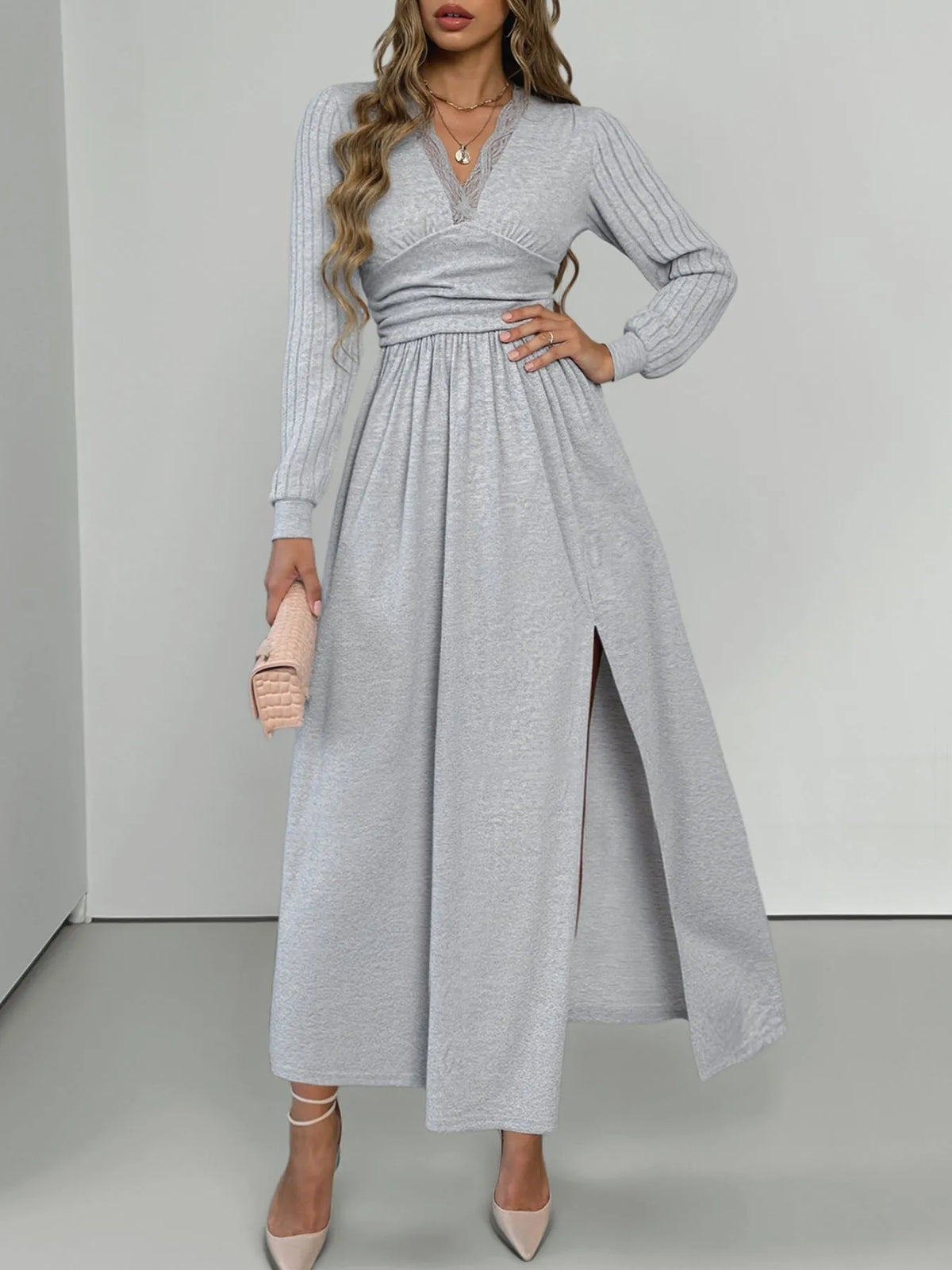 Woman wearing a gray long-sleeve dress with a slit on a white background