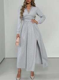 Woman wearing a gray long-sleeve dress with a slit on a white background