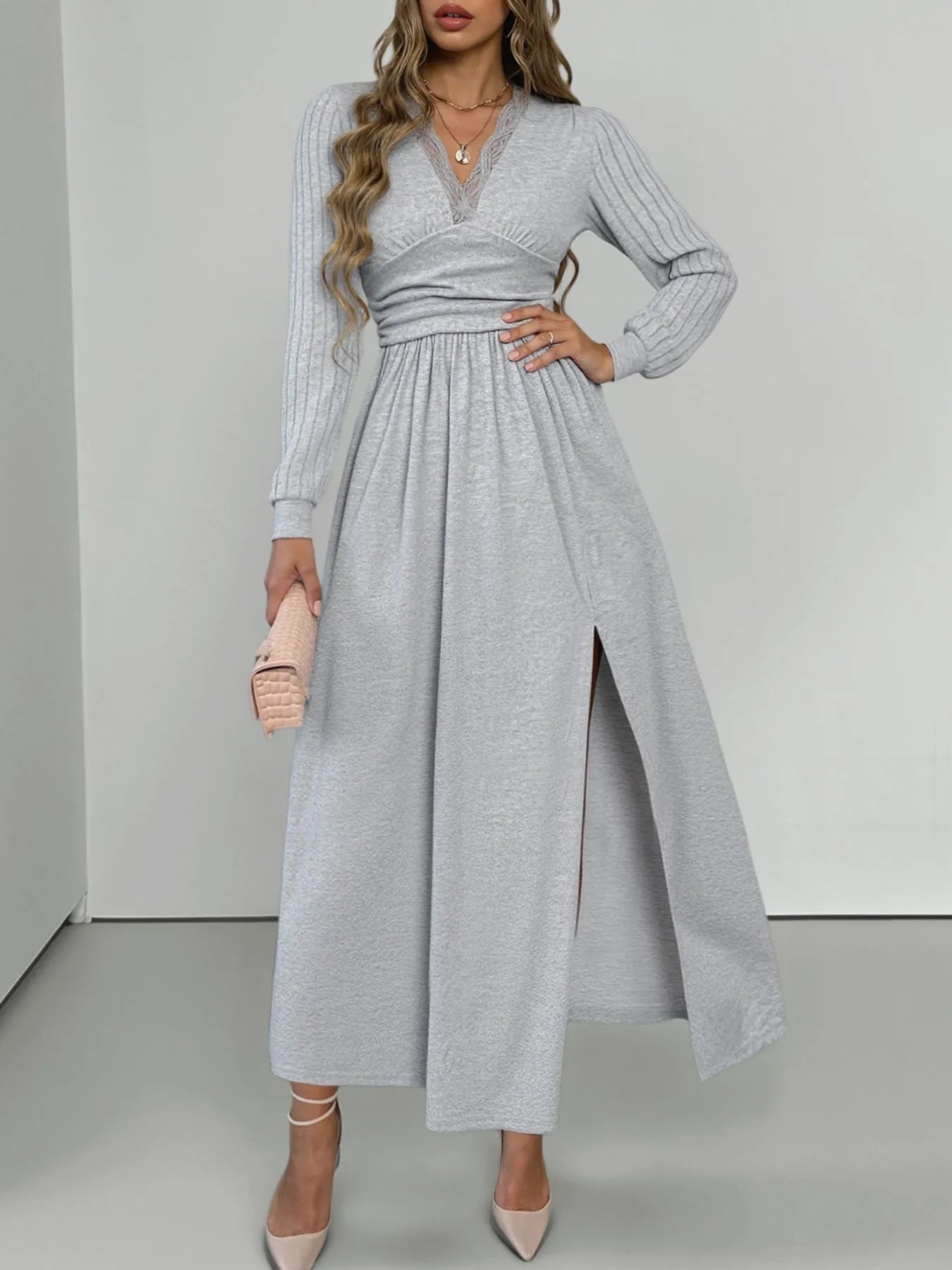 Woman wearing a gray long-sleeve dress with a slit on a white background
