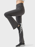 Person wearing black flared pants and black sneakers on a white background