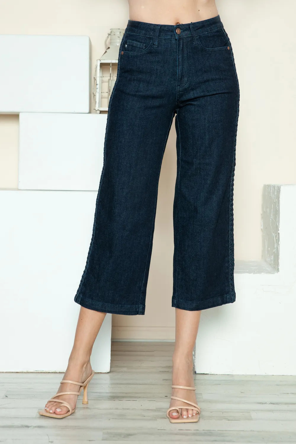 Person wearing dark blue wide-leg jeans in a minimal indoor setting
