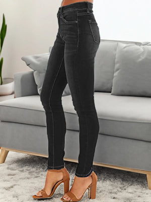 Person wearing black jeans and brown shoes in a living room setting