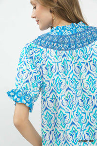 Woman wearing a blue and white patterned blouse with a white background