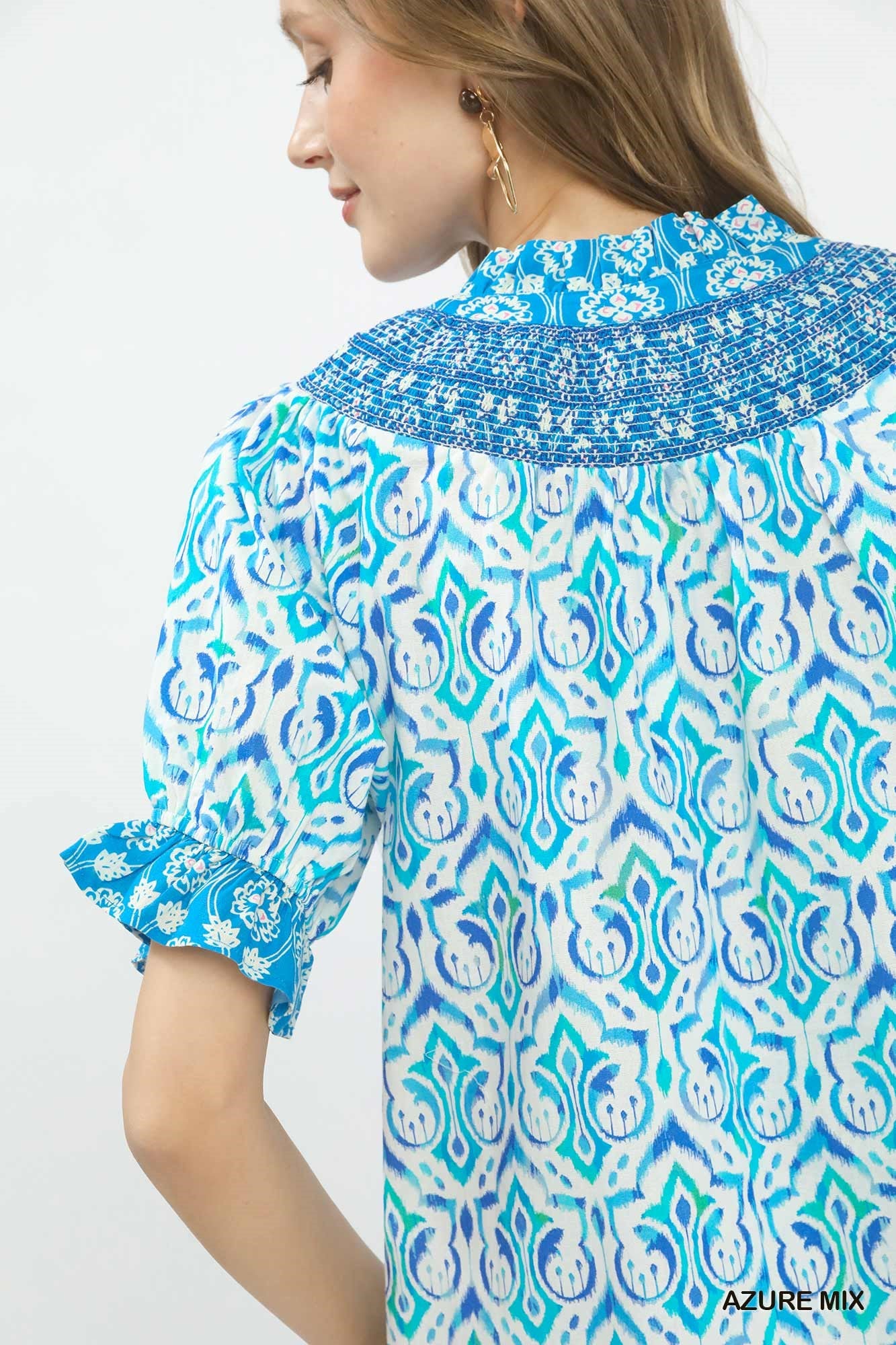 Woman wearing a blue and white patterned blouse with a white background