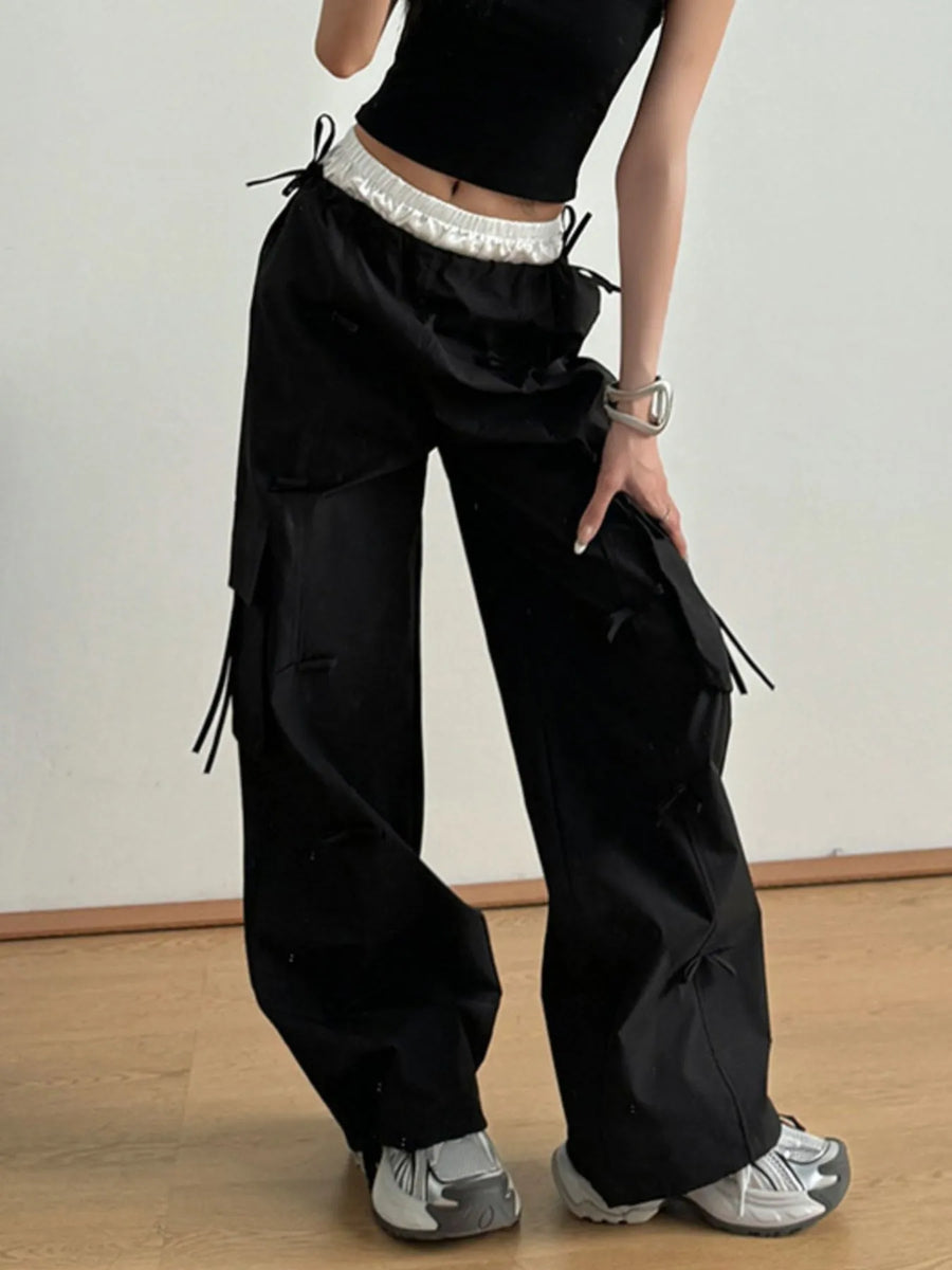 Person wearing black cargo pants with a plain background