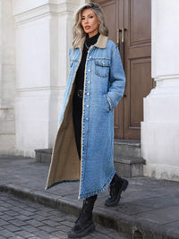 Woman wearing a long denim coat with fur trim standing on a street.