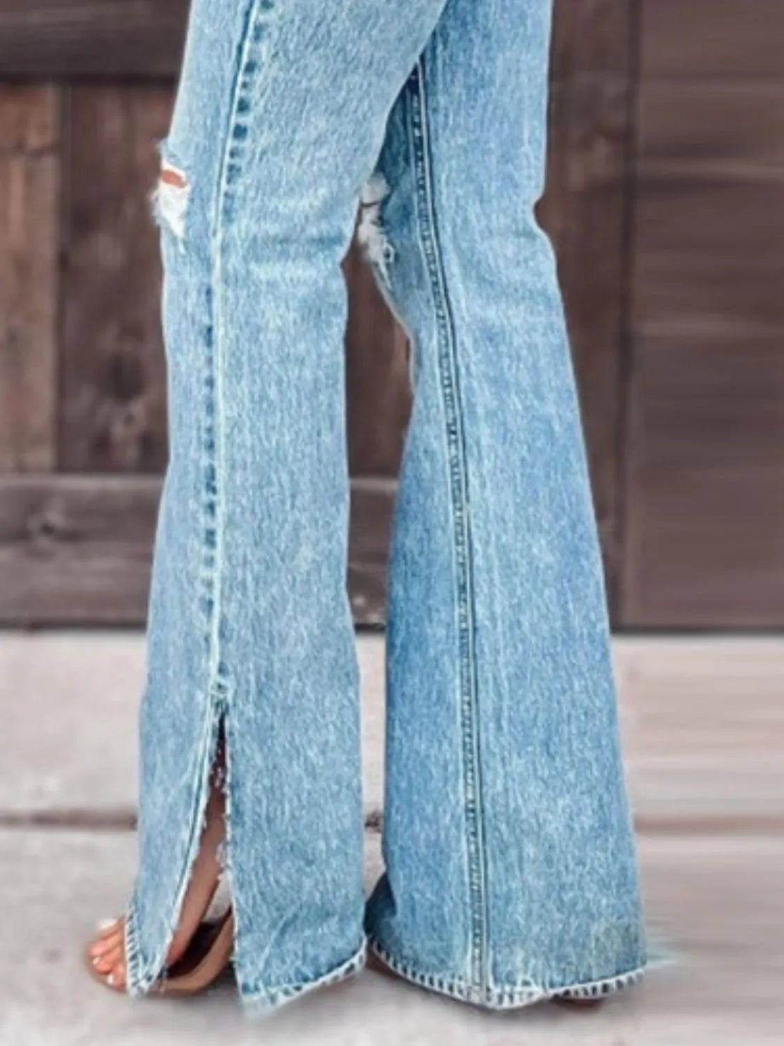 Light blue jeans with a high slit on a wooden floor.