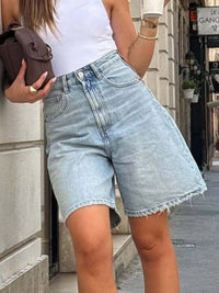 Person wearing light blue denim shorts and a white top on a city street.
