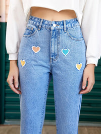 Blue jeans with heart-shaped patches worn by a person.