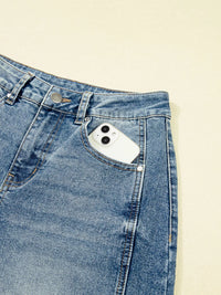 Close-up of a blue denim pocket with a smartphone inside on a beige background