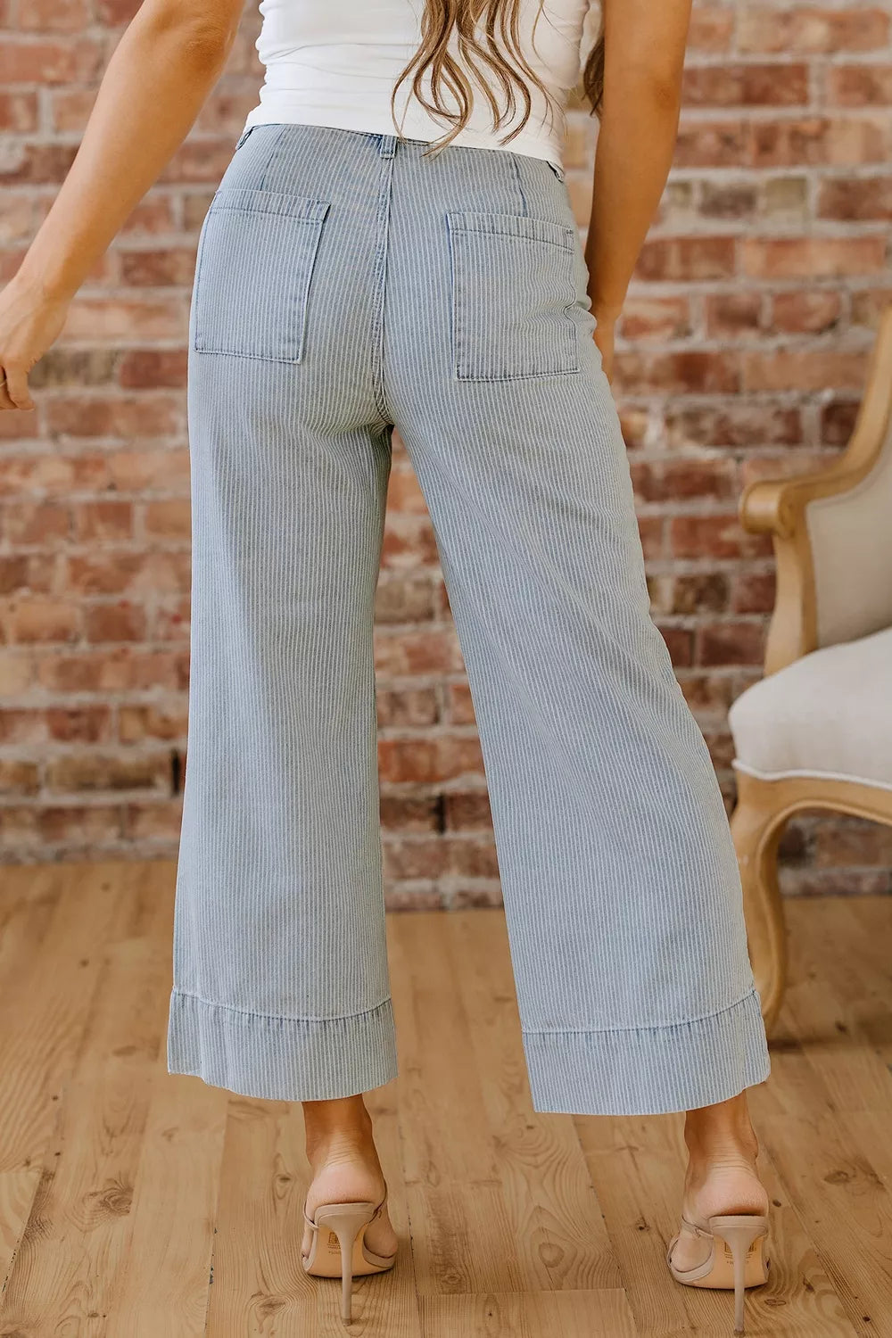 Light blue wide-leg pants worn by a person against a brick wall.