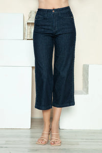 Person wearing dark blue jeans in a minimal indoor setting