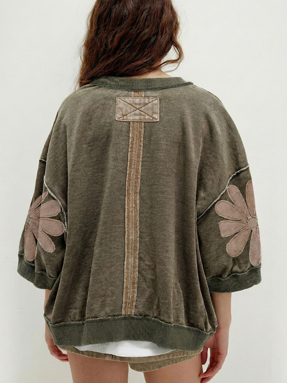 Person wearing a green sweater with floral patterns on a white background