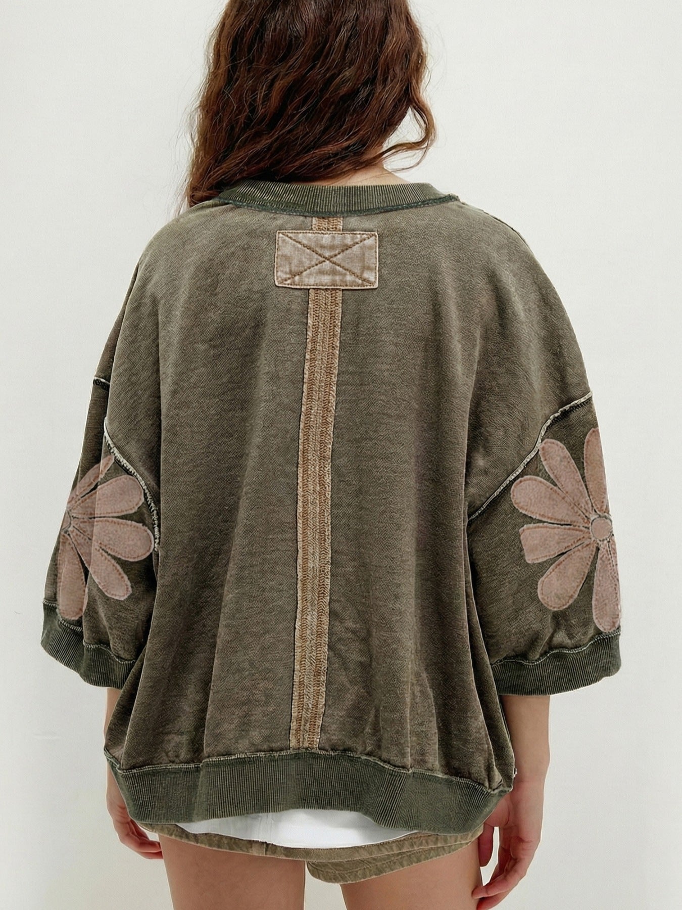 Person wearing a green sweater with floral patterns on a white background
