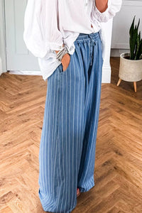 Person wearing blue striped pants and a white shirt on a wooden floor.