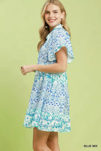 Woman wearing a blue and green floral dress on a light green background