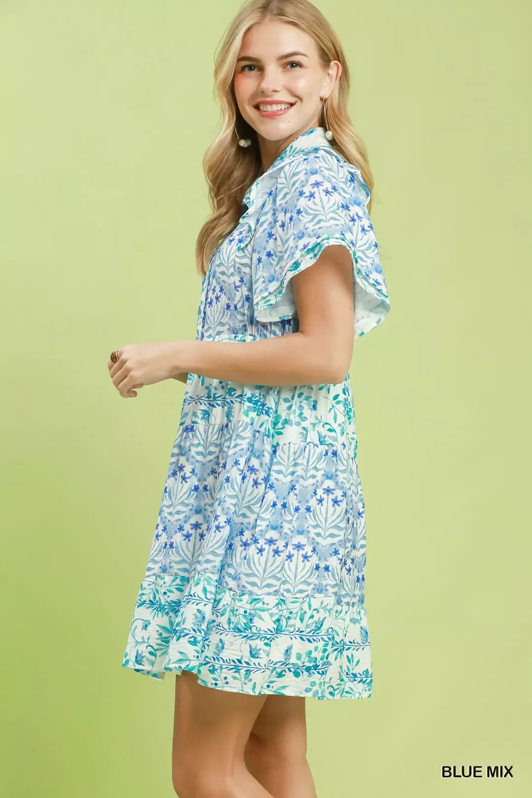 Woman wearing a blue and green floral dress on a light green background