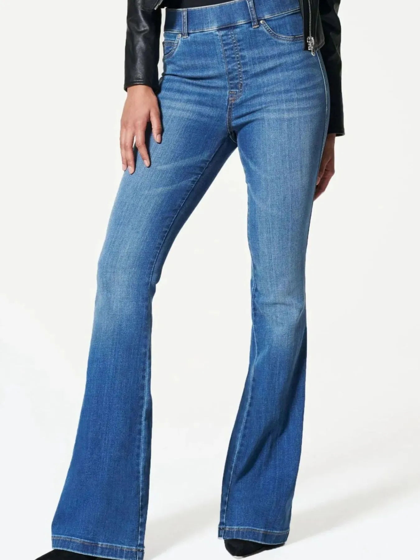 Blue flared jeans worn by a person on a white background