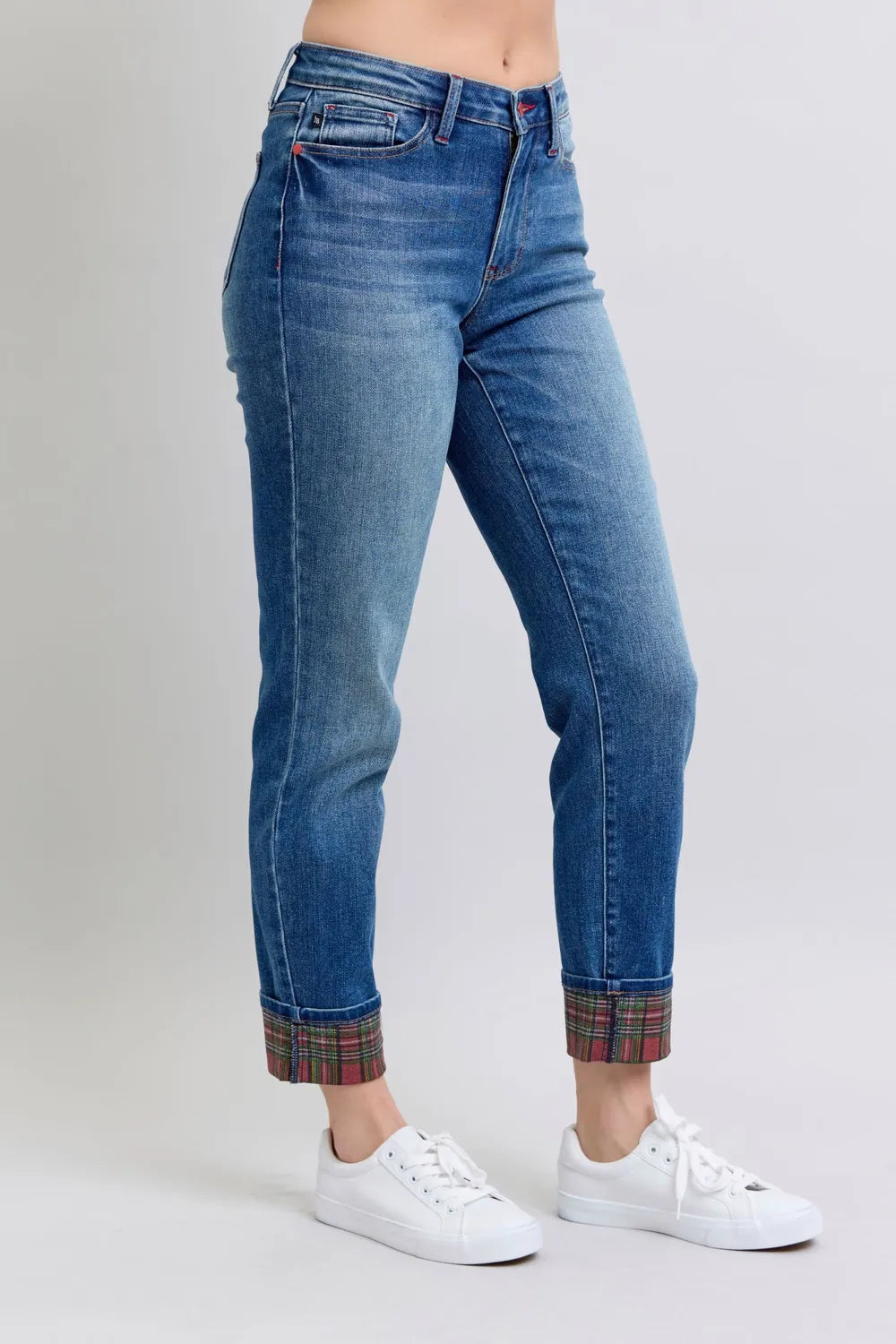 Blue jeans with plaid cuffs worn by a person on a white background