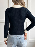 A woman shown from the back wearing a dark navy cable-knit sweater with contrasting cream ribbed collar, cuffs, and hem, paired with light-wash jeans.