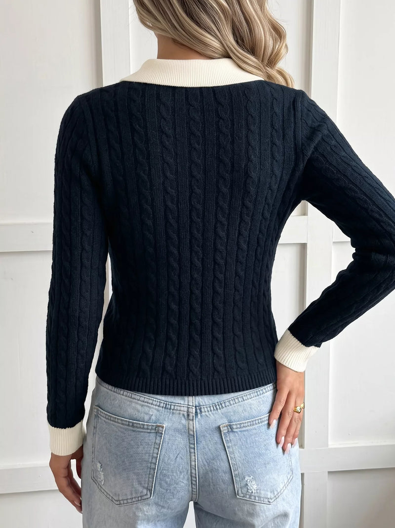 A woman shown from the back wearing a dark navy cable-knit sweater with contrasting cream ribbed collar, cuffs, and hem, paired with light-wash jeans.