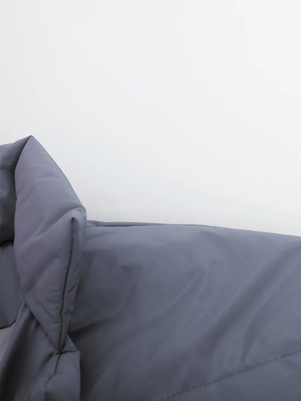 Gray comforter on a bed with a white background