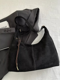 Black leather handbag with a strap on a textured surface