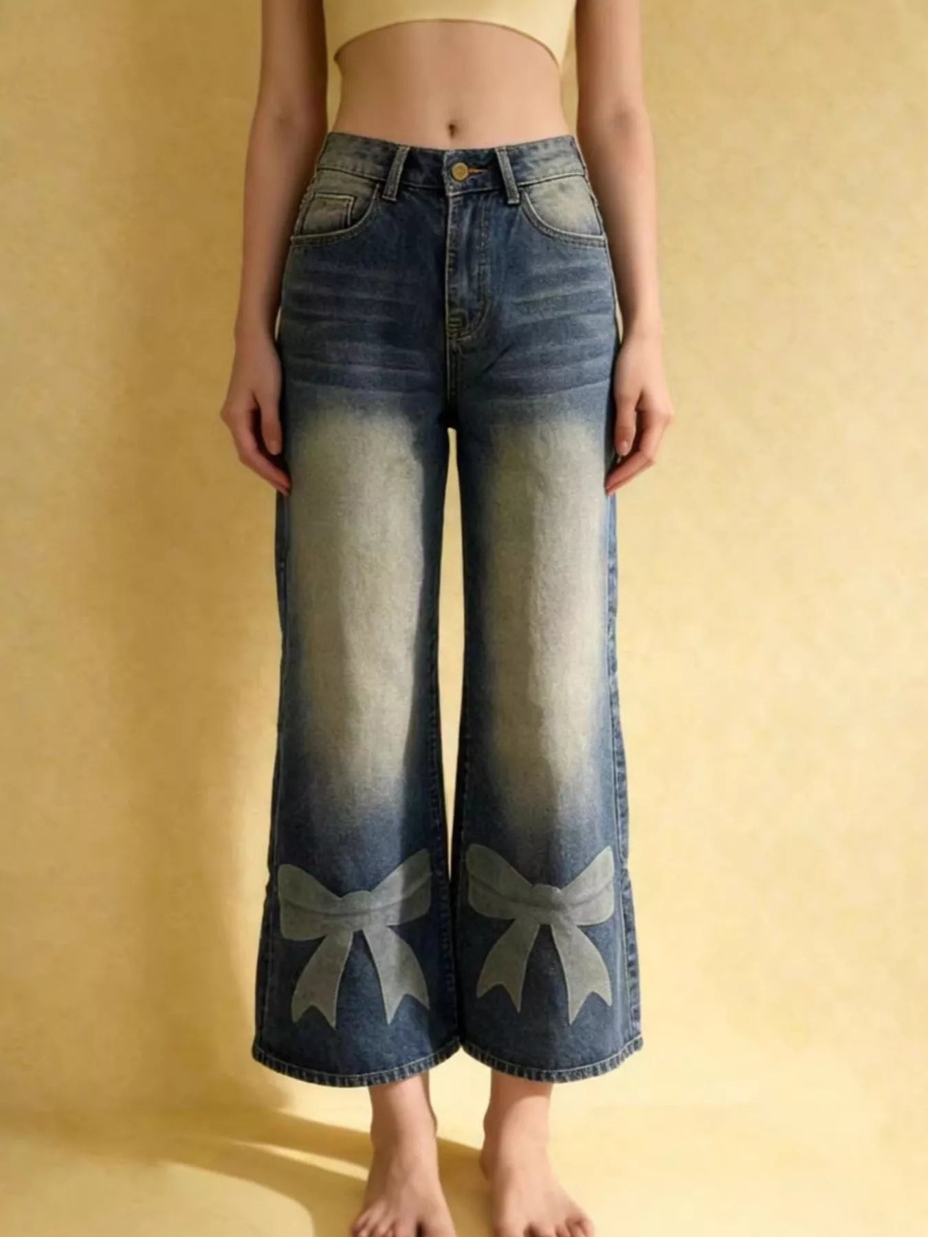 Person wearing blue jeans with bow designs on a yellow background